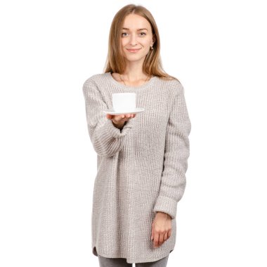 Bir beyaz Kupası ve fincan tabağı, elinde tutan kazaklı genç kadın sıcak kahve içme.