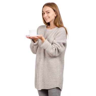 Bir beyaz Kupası ve fincan tabağı, elinde tutan kazaklı genç kadın sıcak kahve içme.