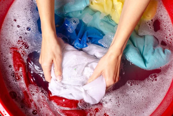 Женщины стирают цветную одежду в умывальнике порошковым моющим средством — стоковое фото