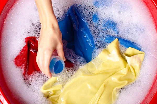 Women washing color clothes in basin enemale powdered detergent liquid laundry gel — Stock Photo, Image