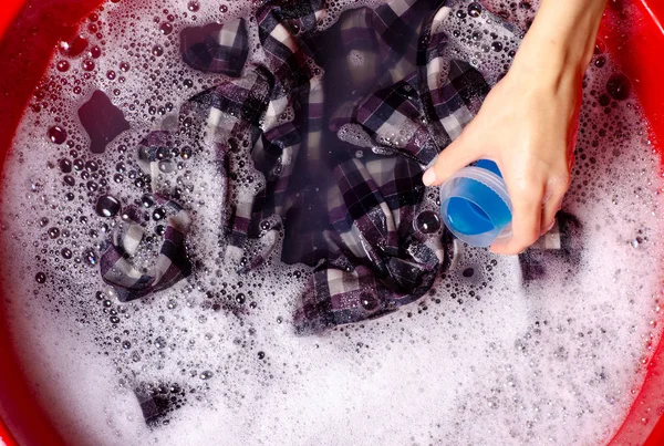 Женщины стирают рубашку цвета одежды в раковине эмали порошок моющего средства жидкий гель для стирки — стоковое фото