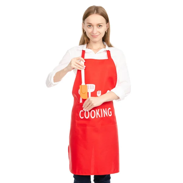 Seorang wanita di celemek merah di tangan spatula dapur — Stok Foto