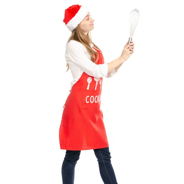 Egy nő, egy piros kötény santa kalap a kezében egy konyha habverővel corolla — Stock Fotó