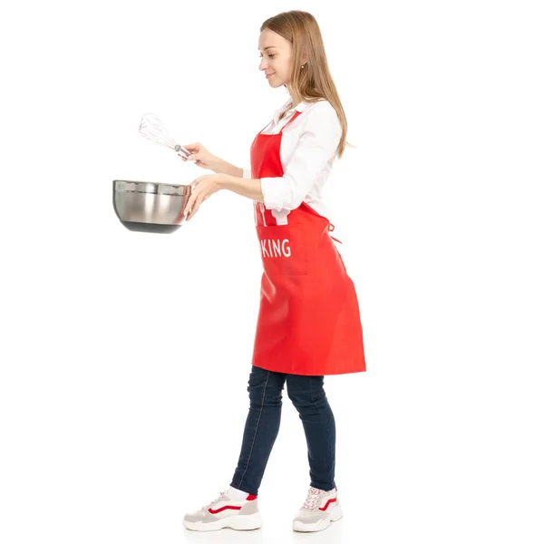 Egy nő, egy piros kötény, a kezében egy konyha habverővel corolla tál — Stock Fotó
