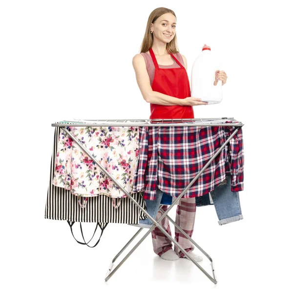 Kvinna i förkläde torkskåp rack med rena kläder plastflaska för flytande tvättmedel — Stockfoto