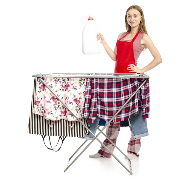 Mulher em prateleira de secagem de roupas de avental com garrafa de plástico de roupas limpas para detergente líquido — Fotografia de Stock