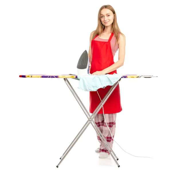 Schöne Frau in Schürze, die mit einem Bügeleisen ein Hemd auf dem Bügelbrett bügelt — Stockfoto