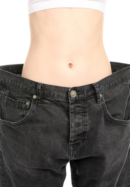 Žena ukazuje její úbytek na váze tím, že nosí staré džíny — Stock fotografie