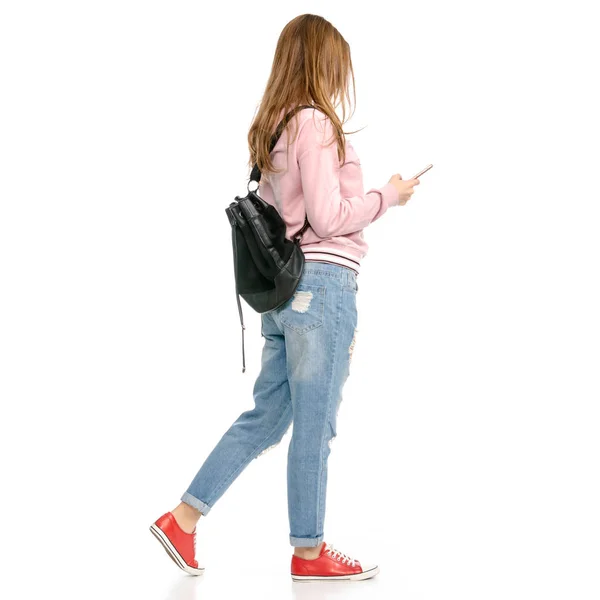 Mooie vrouw in jeans met een rugzak en een mobiele telefoon-smartphone — Stockfoto
