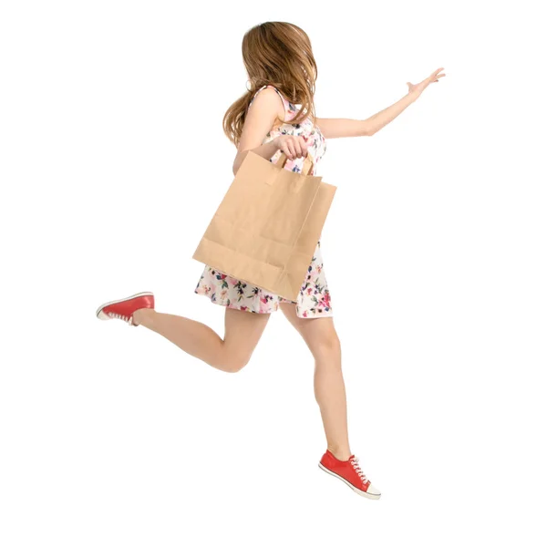 Bella donna in abito con stampa fiori e scarpe da ginnastica che mostrano di emozioni positive corre con pacchetto borsa — Foto Stock