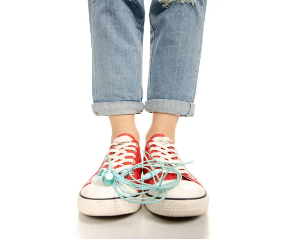 Kadın bacaklar ayak kot kırmızı spor ayakkabılar hippi tarzı kulaklıklar ile — Stok fotoğraf