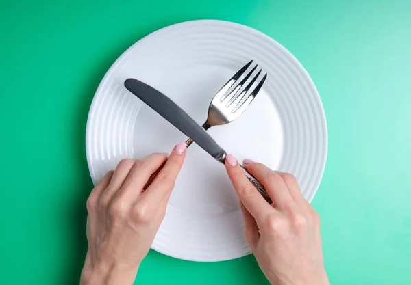 plate fork knife in hand on green background