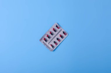 Blister siyah kırmızı kapsül üzerinde mavi arka plan, üstten görünüm