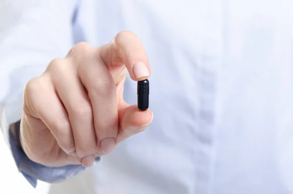 Medicina pílula cápsula preta na mão mulher — Fotografia de Stock