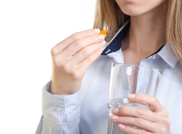 Pastilla de la cápsula naranja y vaso de agua en la mano de la mujer —  Fotos de Stock