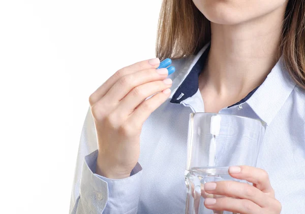Comprimido cápsula azul e vidro de medicina água na mão da mulher — Fotografia de Stock