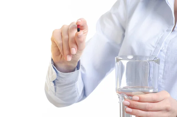 Comprimido cápsula preta vermelha e vidro de medicina da água na mão da mulher — Fotografia de Stock