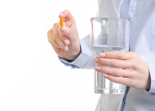 Comprimido cápsula laranja e vidro de medicina água na mão da mulher — Fotografia de Stock
