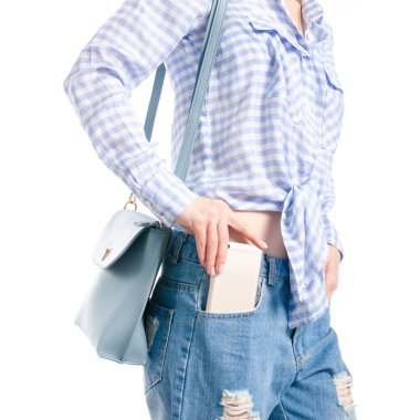 Woman in jeans and blue shirt bag put smartphone pocket in hand macro on white background isolation clipart