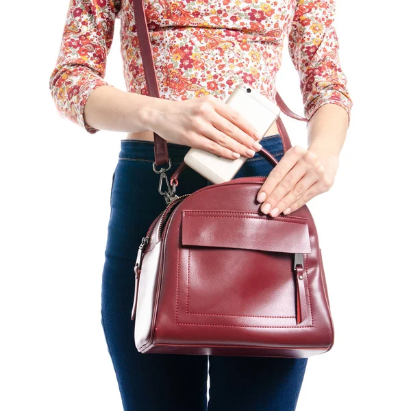 Mulher de jeans azul e camisa colocar smartphone em saco vermelho macro — Fotografia de Stock