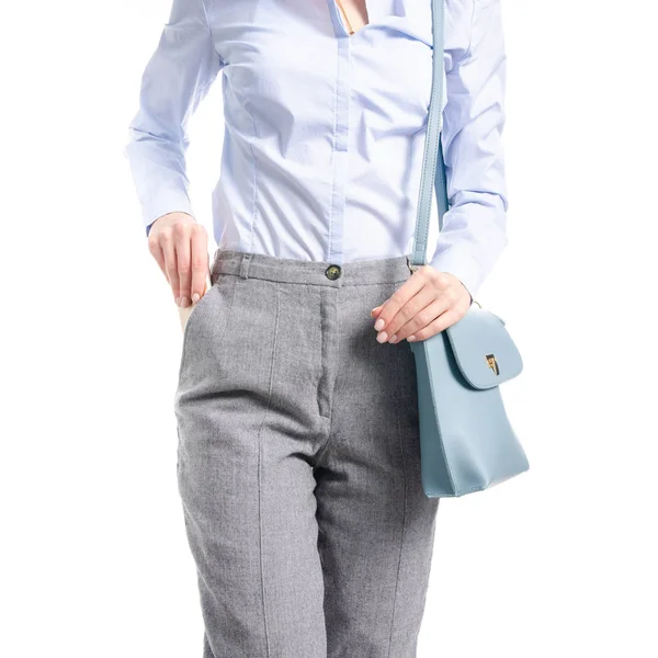 Mulher em calças cinza e camisa azul saco azul colocar smartphone no bolso macro Imagem De Stock