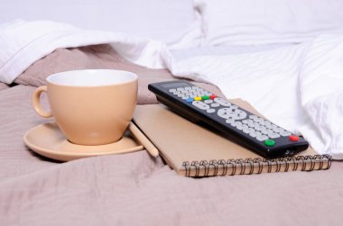 Kahve fincan tabağı Not defteri kalem Tv beyaz yatak kahverengi battaniye var uzaktan ile