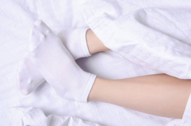 Beyaz çarşaflar yatakta beyaz çoraplı kadın bacakları