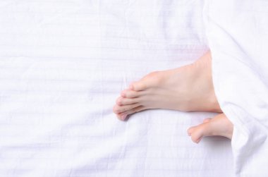 Beyaz yatakta kadın bacakları güzellik