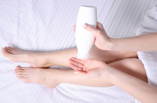 Femme appliquant de la crème pour le corps sur sa jambe dans la chambre à coucher gros plan — Photo