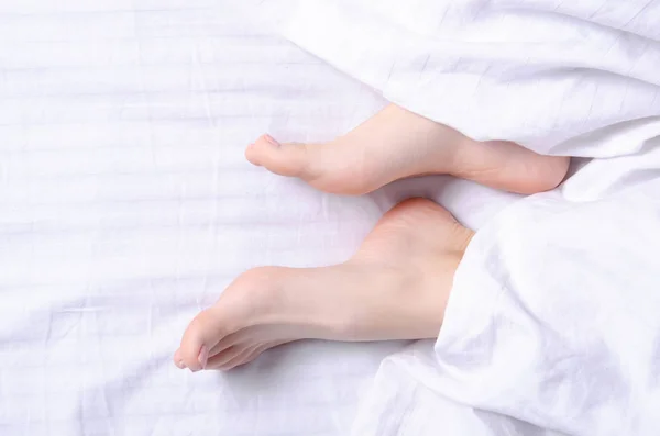 Weibliche Beine Schönheit auf weißem Bett — Stockfoto