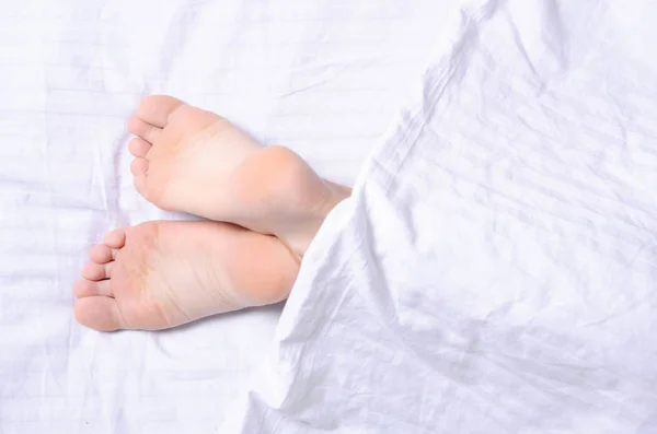 Piernas femeninas belleza en la cama blanca — Foto de Stock