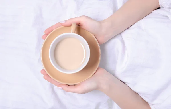 Beyaz çarşaflar yatakta kahve tutan kadın — Stok fotoğraf