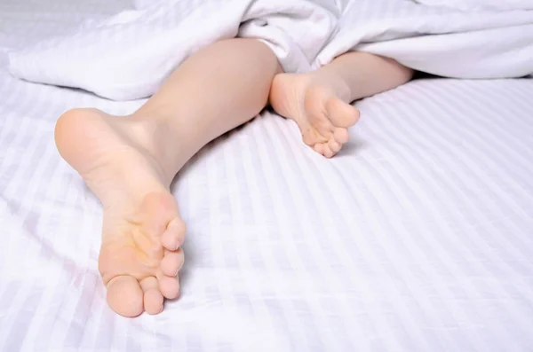 Weibliche Beine Schönheit auf weißem Bett — Stockfoto
