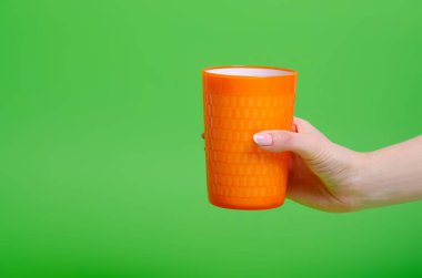 Turuncu plastik su bardağı eline