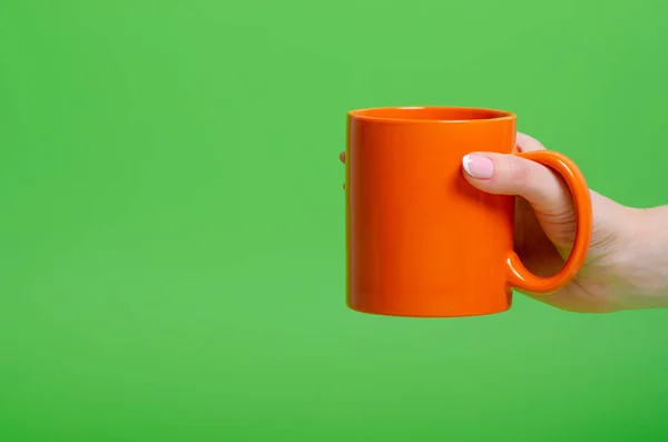 Orange cup mug in hand — Stock Photo, Image