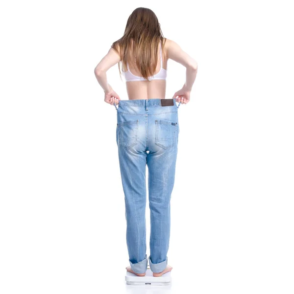 Beautiful woman in big jeans on weighing-machine, weight loss slimming — Stock Photo, Image
