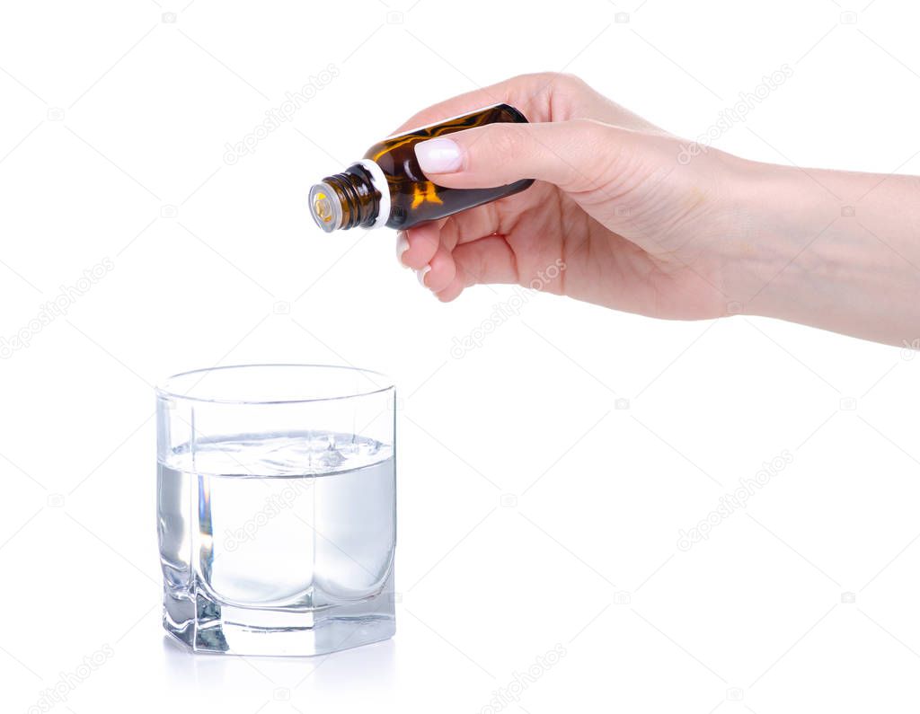 the medicine bottle in hand drips into a glass of water