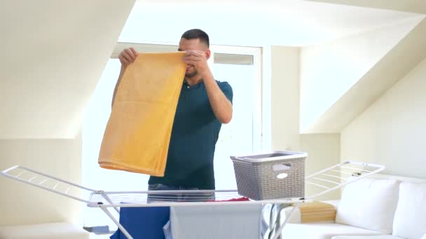 Чоловік бере білизну з сушильної стійки вдома — стокове відео