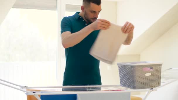 Mann holt Wäsche aus Wäscheständer zu Hause — Stockvideo