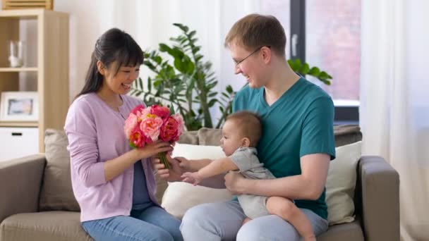 Glückliche Familie mit Blumen und Baby zu Hause — Stockvideo