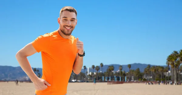 Smiling young man running at summer seaside — Stock Photo, Image