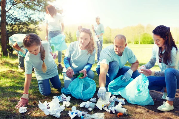 Relawan dengan kantong sampah membersihkan area taman — Stok Foto