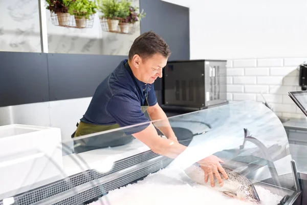 Vendedor masculino colocando truta para geladeira na loja de peixe — Fotografia de Stock