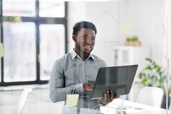 Businessman with laptop at office glass board — Stock Photo, Image