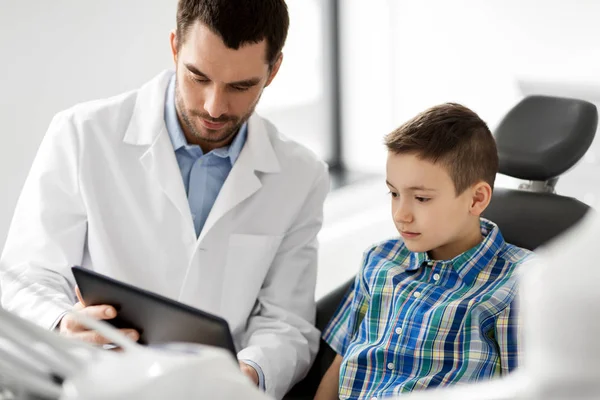 Dentista che mostra tablet pc al paziente bambino presso la clinica — Foto Stock