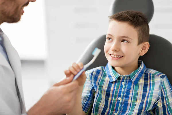 Çocuk hasta kliniğinde diş fırçası veren diş hekimi — Stok fotoğraf