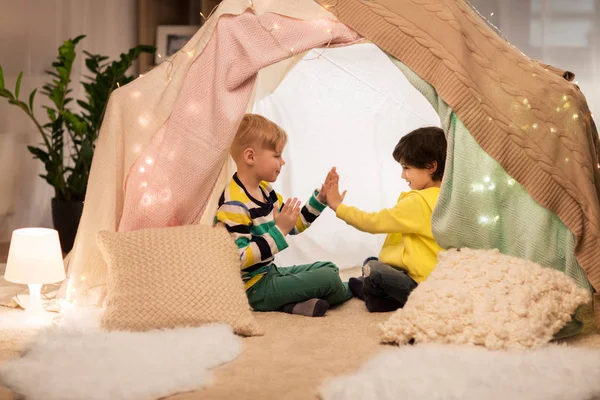 Мальчики играют в аплодисменты в детской палатке дома — стоковое фото