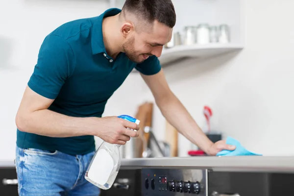 Man met doek reinigen kookplaat op huis keuken — Stockfoto