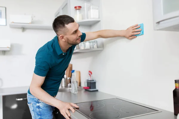 Uomo con straccio pulizia parete a casa cucina — Foto Stock