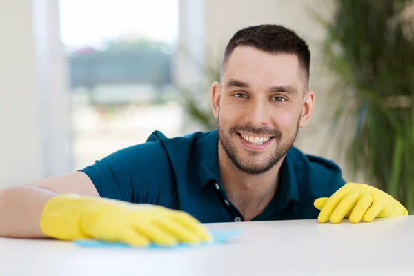 Smiling man cleaning table with cloth at home — Stock Photo, Image